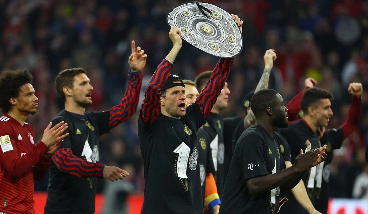Thomas Muller celebrates with a replica trophy